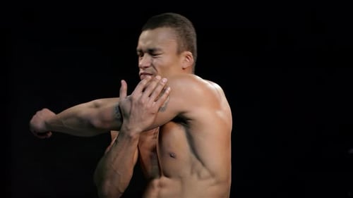 Muscular Man Massages Shoulder in Pain
