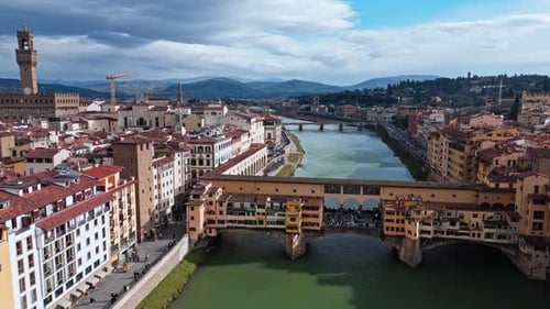 Aerial view of Ponte Vecchio in Florence, Italy, spanning the Arno River with a scenic city backdrop