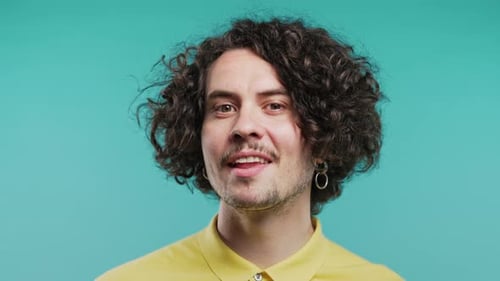 Schöner Mann zwinkert mit den Augen, flirtet und lächelt dem KameraKerl im Blue Studio zu