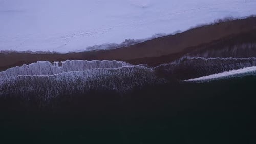Sandy Beach Covered By Snow and Crashing Waves