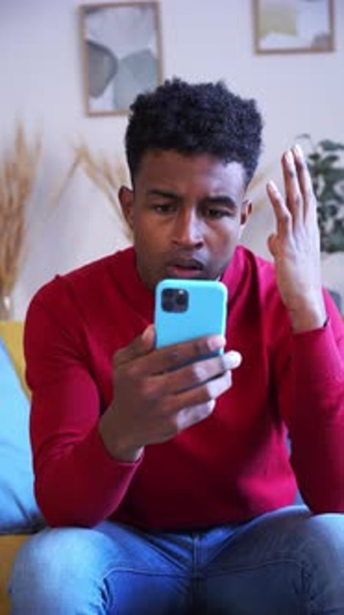 Young Adult Looking Worried at Phone Indoors