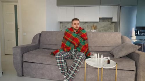 Jeune homme malade ayant froid et frissonnant à la maison