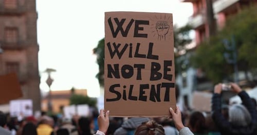Young woman marches with crowd holding banner for justice in the city