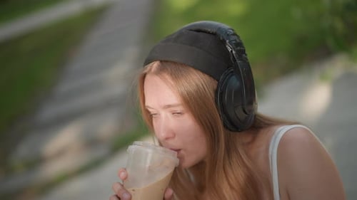 Woman Enjoying Iced Coffee with Headphones Outdoors