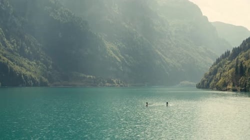 People in stand up paddle in stunning turquoise river landscape. Aerial flying