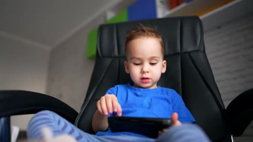 Child Using Smartphone Sitting in a Black Chair