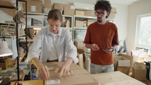 Colleagues Packing Parcels and Using Tablet in Delivery Service Office