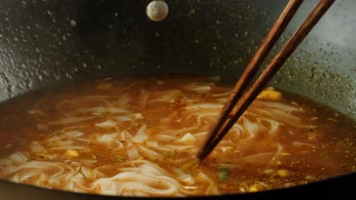 Noodles Raised From a Wok With Chopsticks