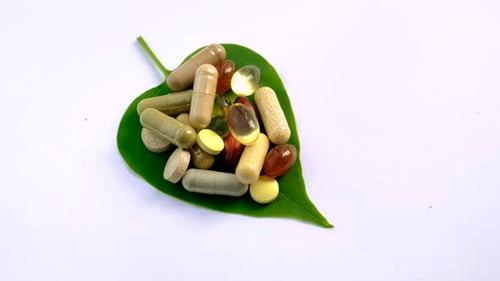 Assorted Pills and Capsules on Green Leaf