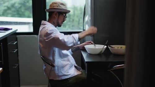Man With Tattoos Eats Salad in Modern Kitchen