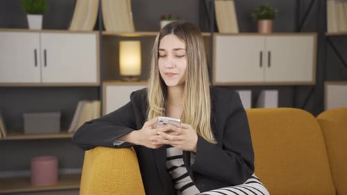 Woman Frustrated with Smartphone on Yellow Couch