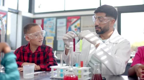 In a school classroom, a biracial teacher demonstrates a chemistry experiment
