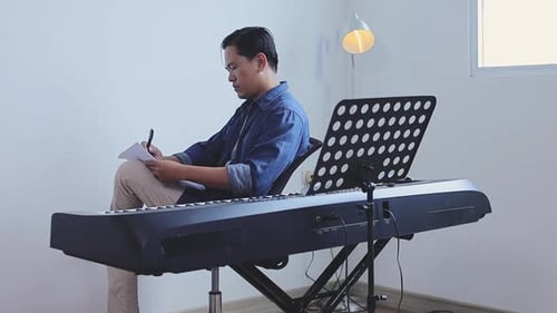 Man Composing Music at Piano Indoors