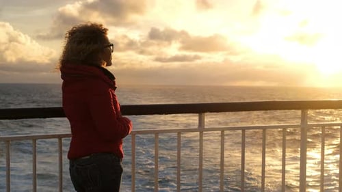 One lady with red winter warm jacket enjoy the sunset on the cruise boa deck during ocean travel