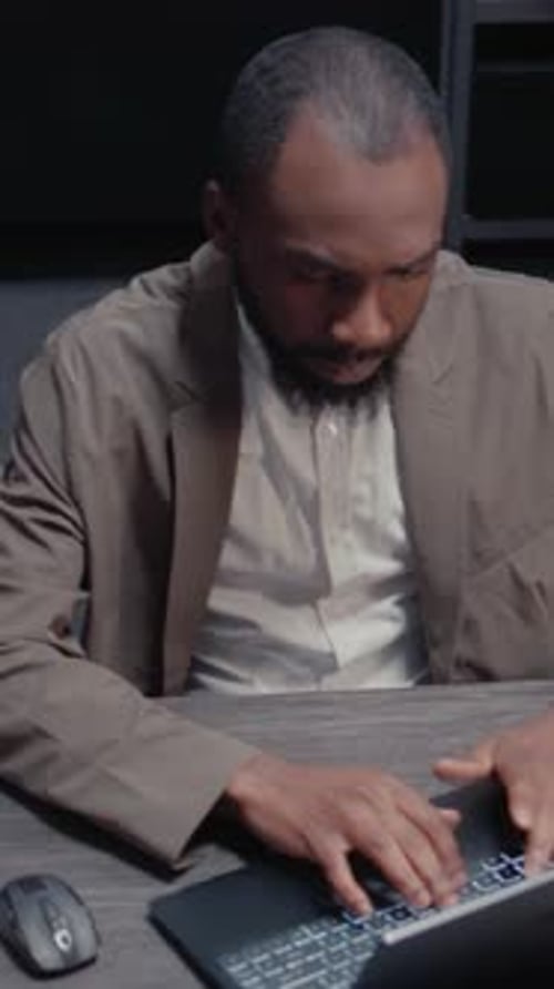 Adult Uses Laptop and Mouse in Dark Office