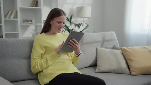 Woman Using Tablet While Relaxing on Couch