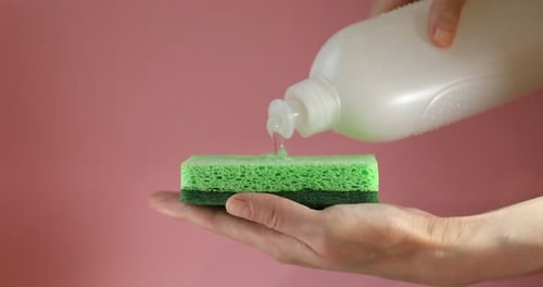 Dish Soap Being Poured on a Green Sponge