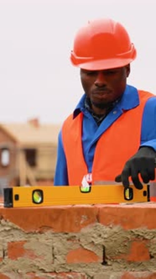 Construction Worker Leveling Brick Wall at Cottage Building Site