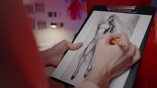 Closeup of Work Process of a Fashion Designer at Clothing Design Studio Drawing Sketch of Dress
