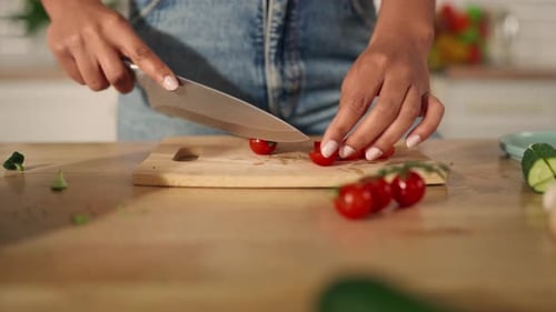 Hands cutting cherry tomatoes in bright kitchen