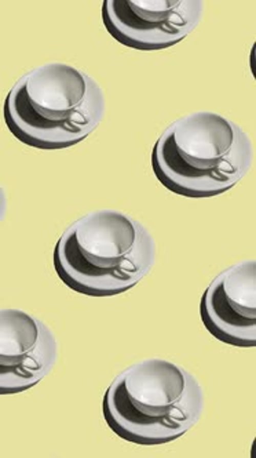 Pattern of Empty Tea Cups with Saucers Casting Shadows on Yellow Background