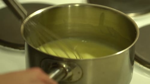Sahnesauce in einer kleinen Pfanne mit dem Metallbesen umrühren, STILL