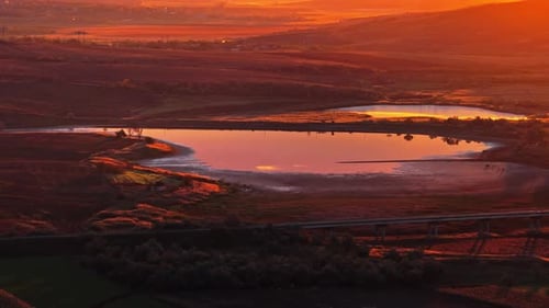 Vista aérea con un dron de un tranquilo lago que refleja la cálida luz dorada del atardecer en la zona rural de Moldavia
