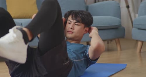 Nahaufnahme eines asiatischen Mannes in Sportkleidung beim Crisscross-Crunch-Training während des Trainings zu Hause