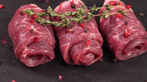 Tortas de vitela frescas aparadas ou carne marmorizada com tomilho e pimenta em grão, vista lateral de pimenta. Flanco