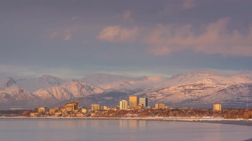 City Skyline with Snow-Capped Mountains at Sunrise