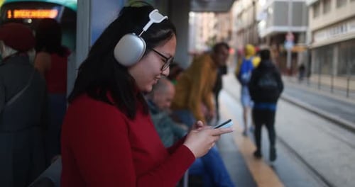 Young Adult Woman Using Phone at Bus Stop