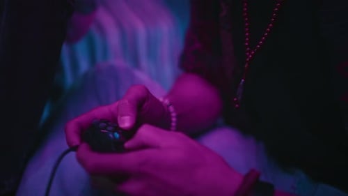 Close-up of Gen Z Guy Holding Gamepad Playing Console with Friend