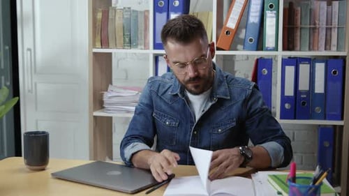 Beau jeune homme intelligent et inspiré, assis près du bureau, écrivant des notes créant de nouvelles idées