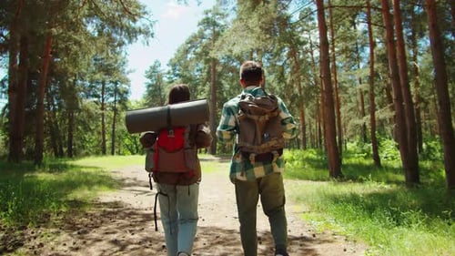Young Couple Tourists Walking in Forest Man and Woman Hikers Traveling Students Hiking Together