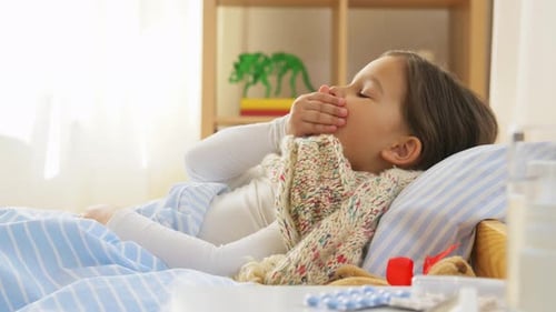 Sick Child Coughing in Bed at Home