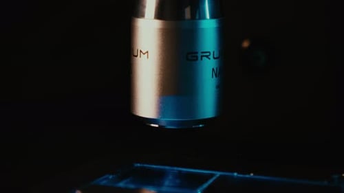 Microscope Lens Examining Slide in Dark Lab