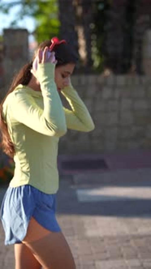 A Woman is Enjoying an Outdoor Jog During the Day Wearing Cozy Earmuffs for Warmth