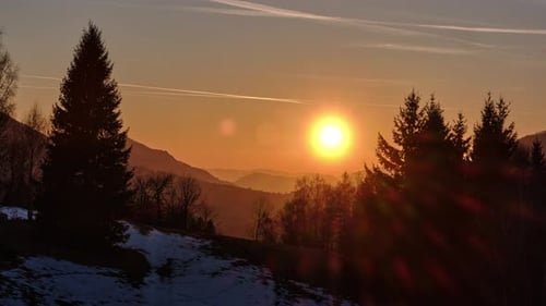 Timelapse of Golden Sunset Over Winter Mountain Landscape with Silhouettes of Spruce Trees