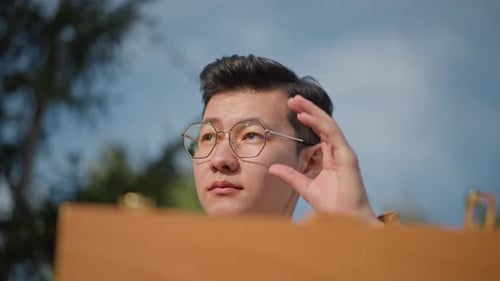 Street Artist Capturing Cityscape with Glasses and Jacket Outdoors Artist Focused on Sketching City