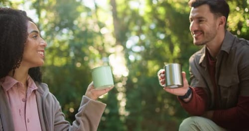 Happy, interracial couple and cheers with coffee in forest for travel date