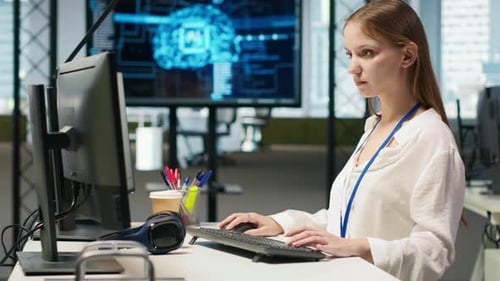 Woman Typing at Computer Workstation in Modern Office