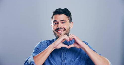Man Makes Heart Shape With Hands and Smiles
