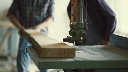 Carpenter Cutting Wood Plank with Bandsaw in Workshop