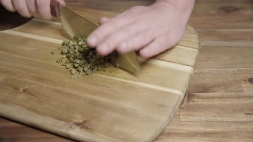 Chef finely chopping, with kitchen ax knife, capers to prepare Paris coffee butter, perfect sauce fo