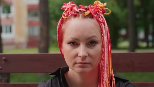 Introspective Urban Performer with Vibrant Hair Contemplative Street Artist Captured Up Close Amid