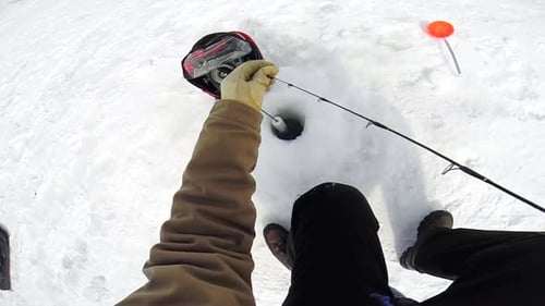 Man Ice Fishing on Frozen Lake in Winter