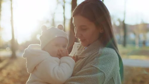 Beautiful Young Caucasian Mother Holding Cute Little Baby Girl in Funny Baby Cap Smiling Toddler and