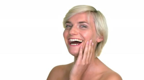 Close up shot of a blonde, short-haired woman, smile and resting her hand upon her face in a studio