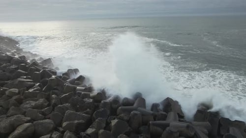 Waves Crashing Against Tetrapod Breakwater on Gray Day