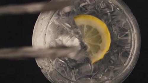 Lemon wedge dropping into ice-filled glass of water